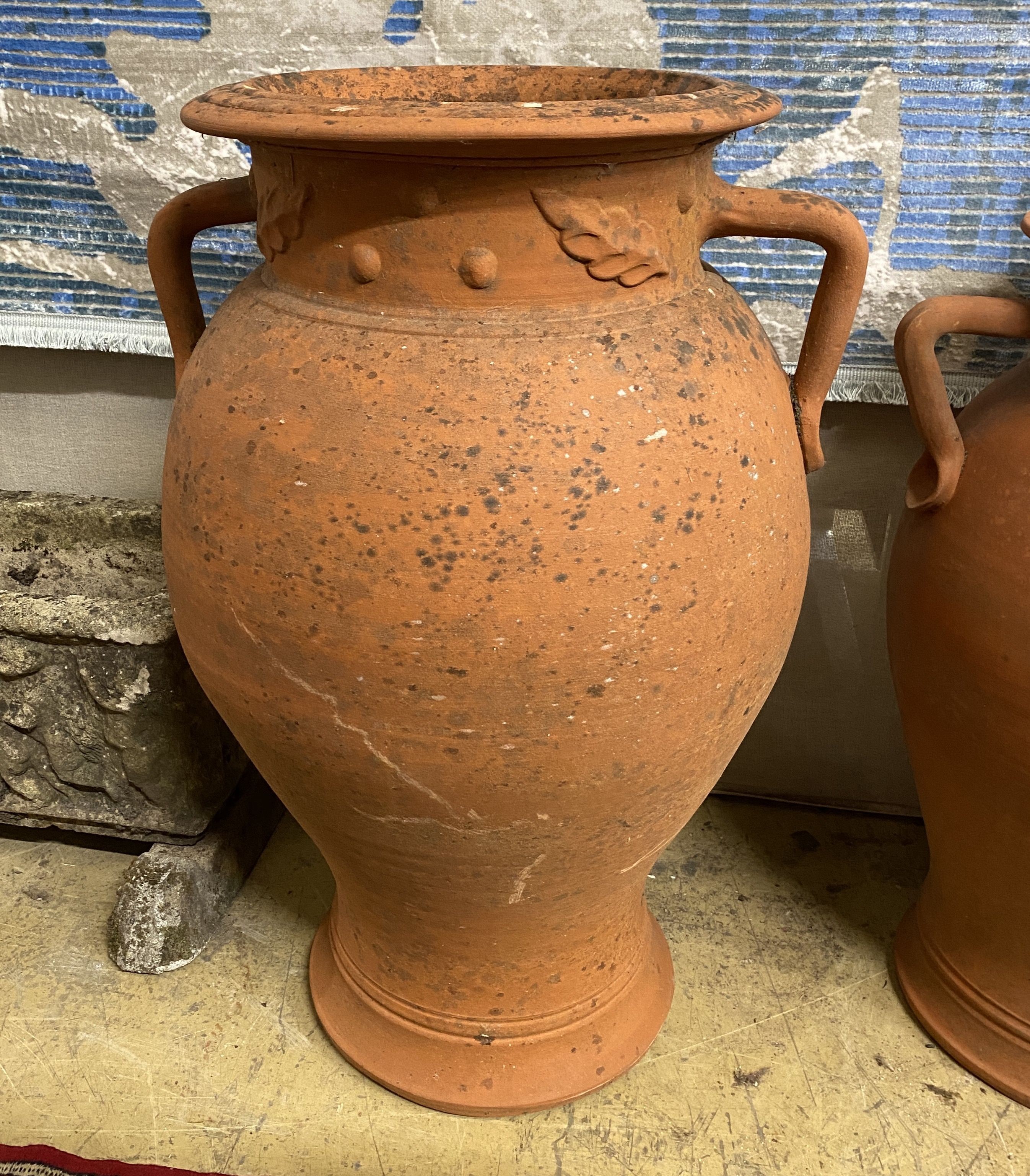 A set of three terracotta baluster garden urns moulded with leaves, largest height 72cm